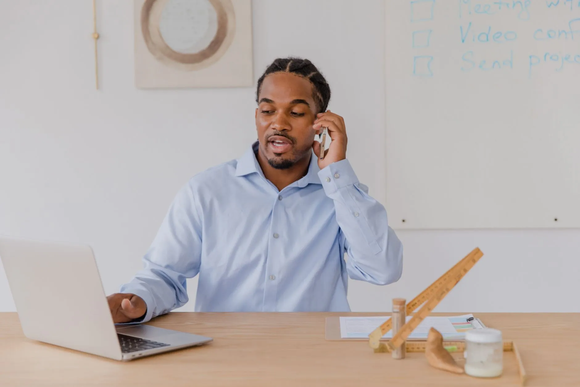 Someone taking a scheduling call at a desk beside a whiteboard of meeting notes