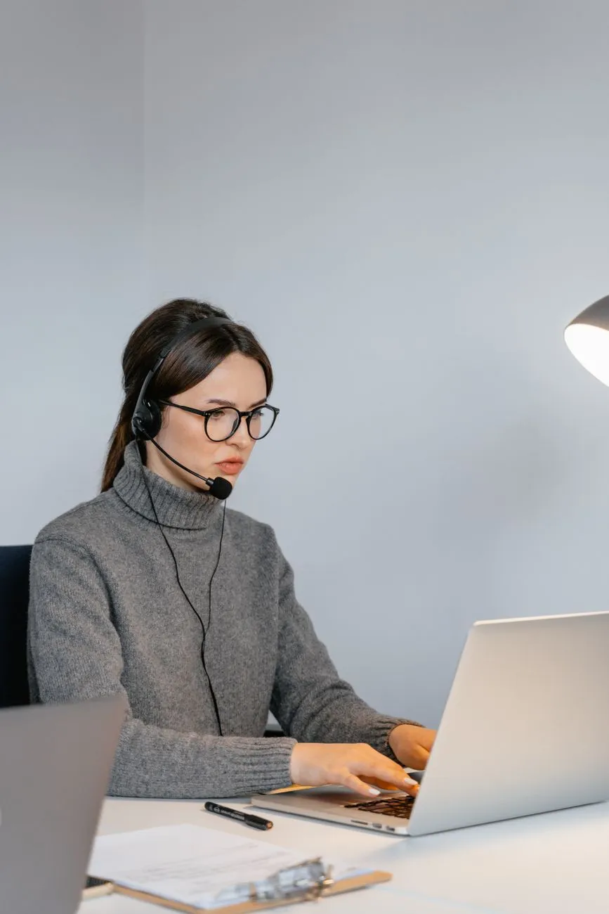Customer support agent wearing a headset while typing on a laptop