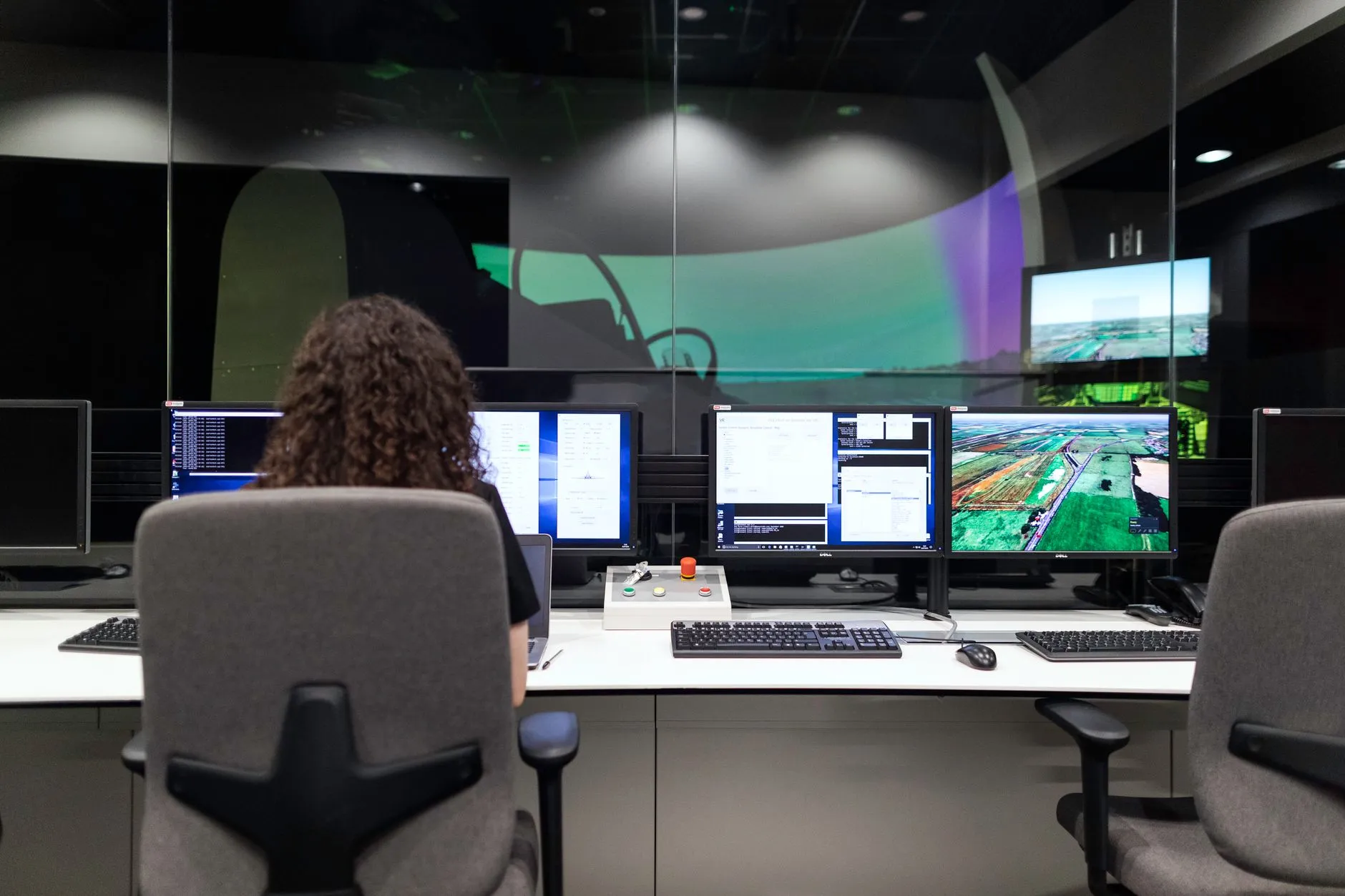 Engineer monitoring multiple screens showing system status and dashboards