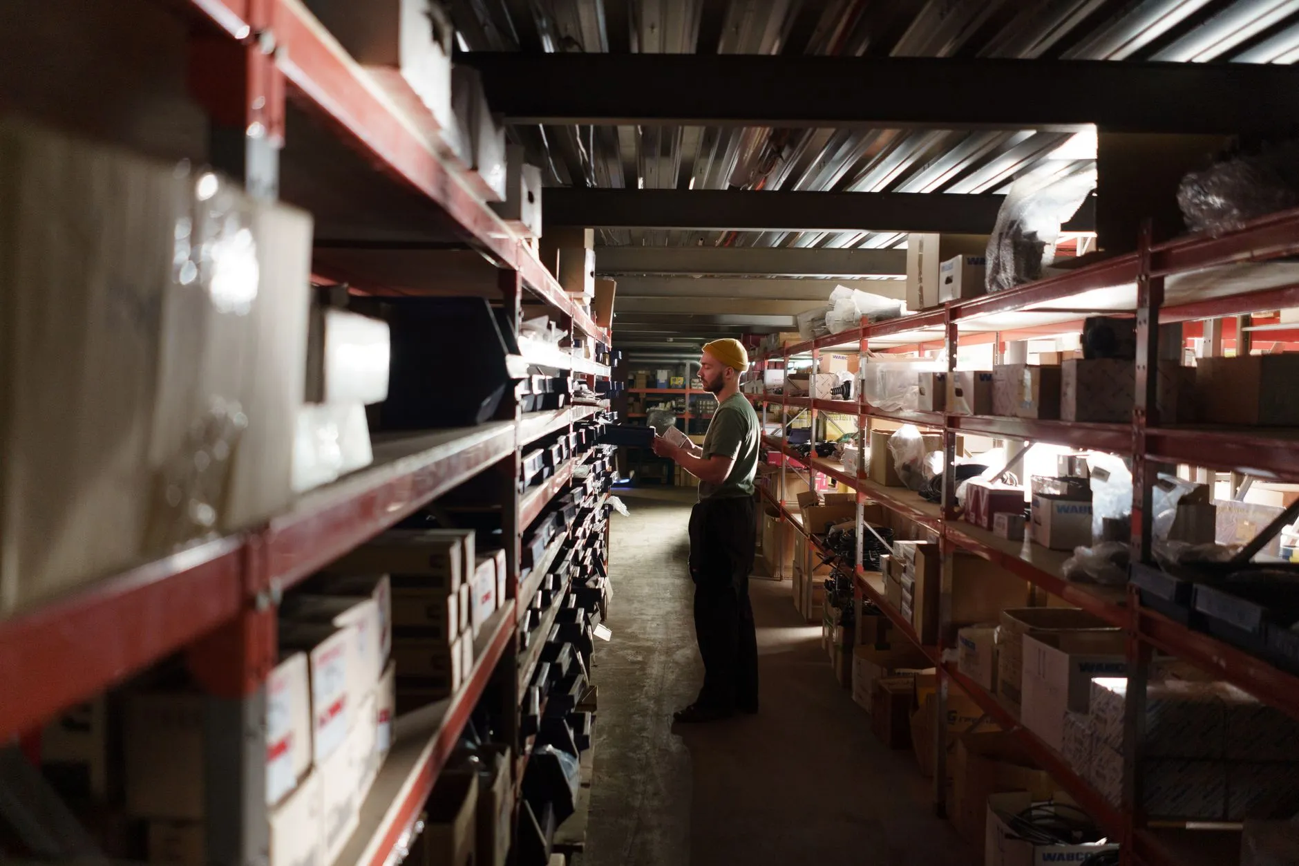 Worker checking inventory on warehouse shelving