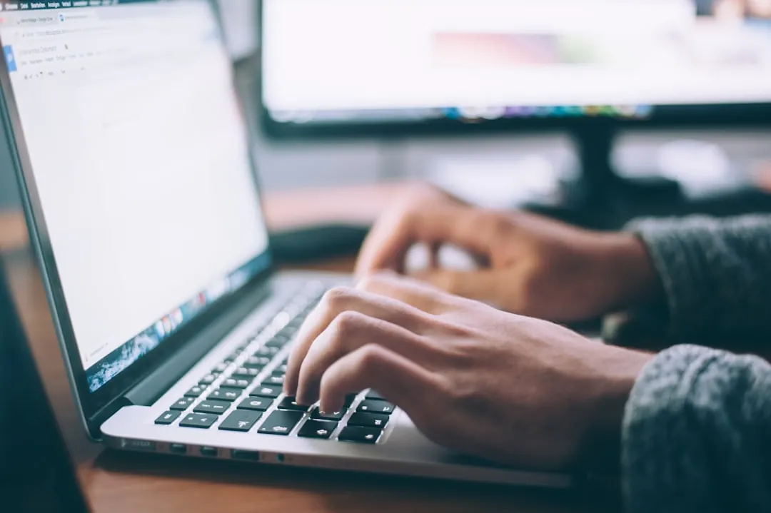 Hands typing documentation into a document on a laptop