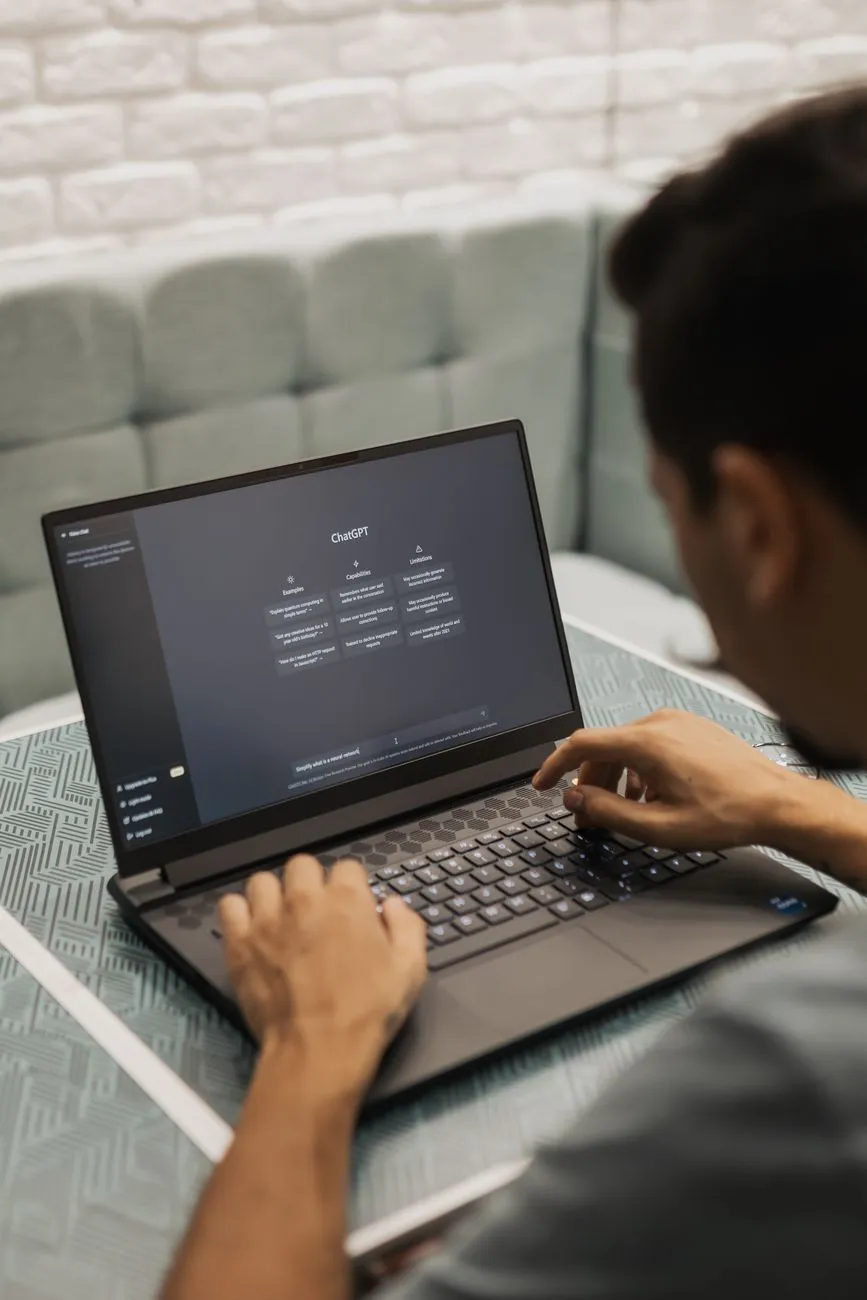 Person typing into a ChatGPT interface on a laptop