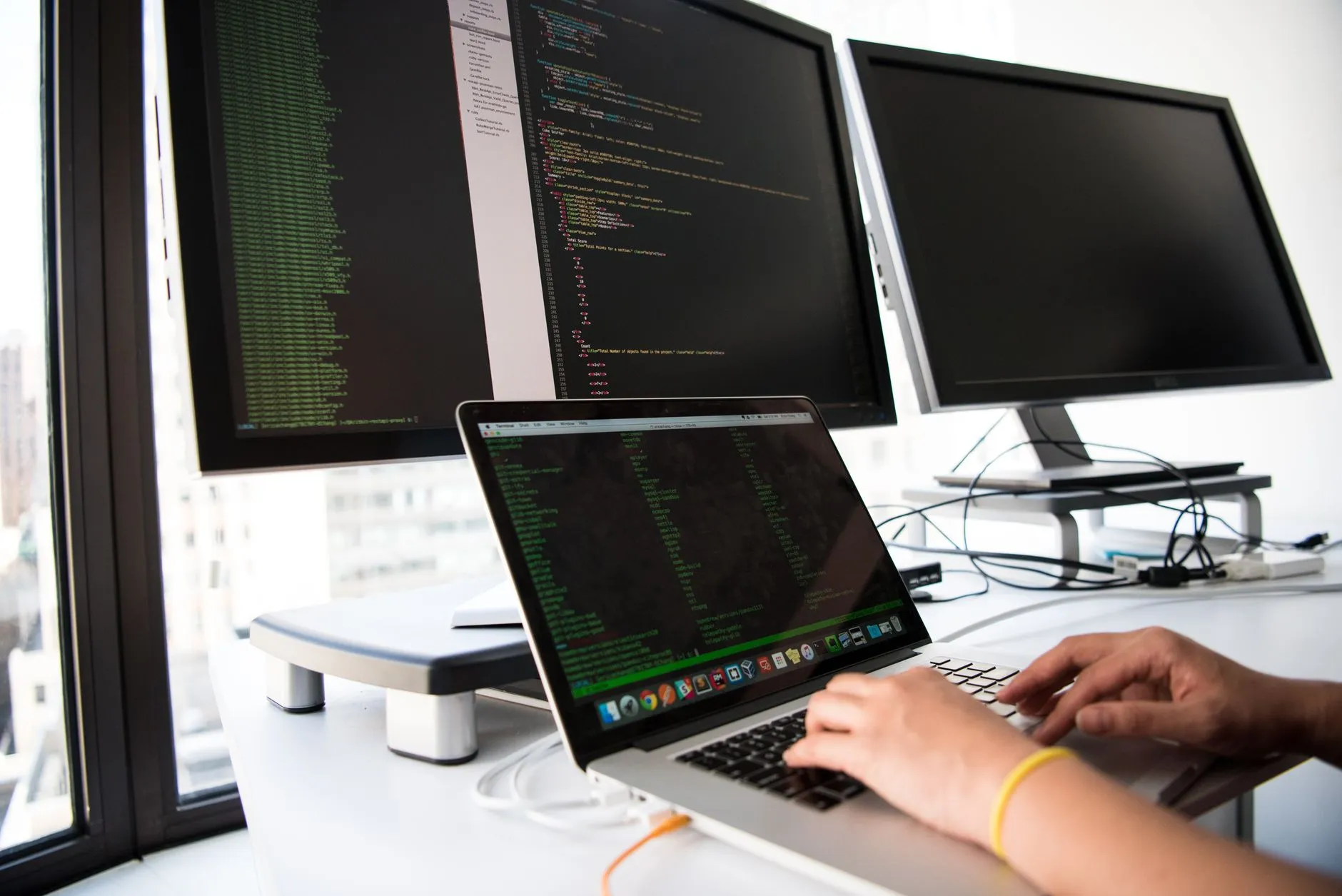 Developer working across three monitors with code editors open