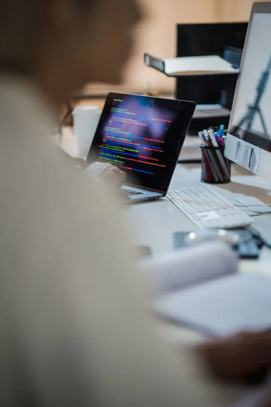 Software developer writing code at a desk in an office