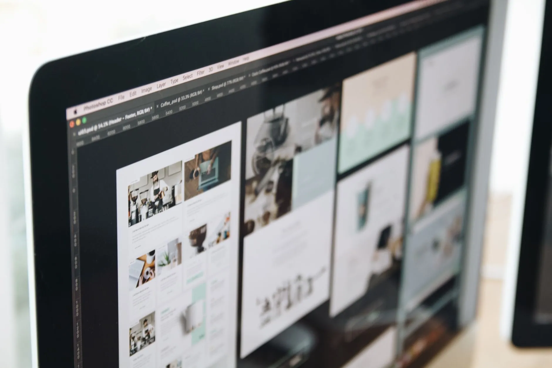 Designer reviewing website layout mockups on a monitor