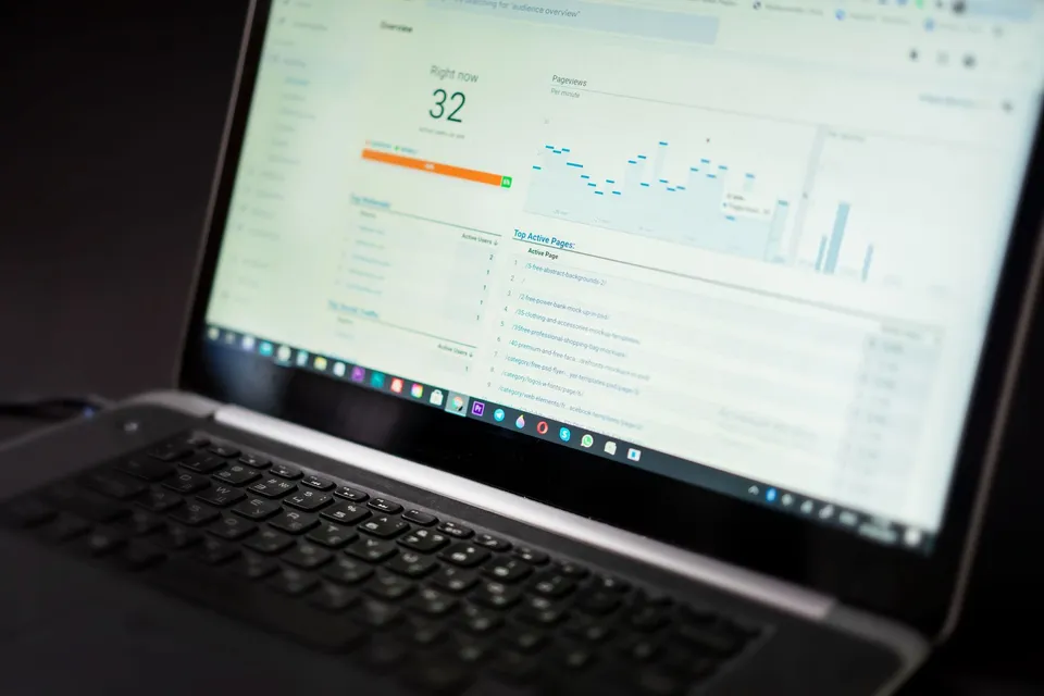 A laptop showing a website analytics dashboard with live users, pageviews, and top active pages